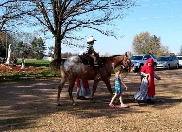 Sisters helping boy ride a horse